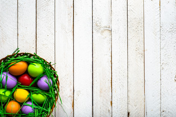 Basket with easter eggs, background with colorful eggs, spring festive decoration on wooden background
