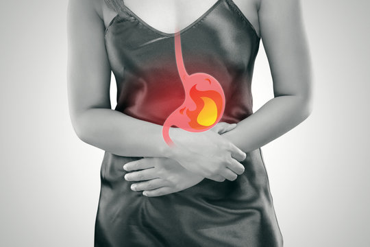 Acid reflux or Heartburn, The photo of stomach is on the woman's body against gray Background, Bad health, Female anatomy concept