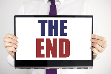 Word, writing The End. Business concept for End Finish Close Written on tablet laptop holding by the man blurred background. Businessman fingers keeping the computer.