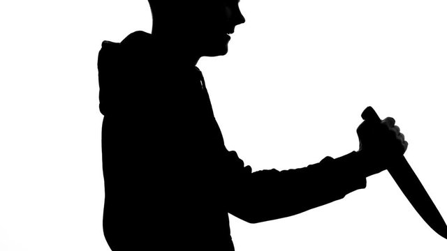 Maniac attacking victim by knife, dangerous criminal committing murder, shadow