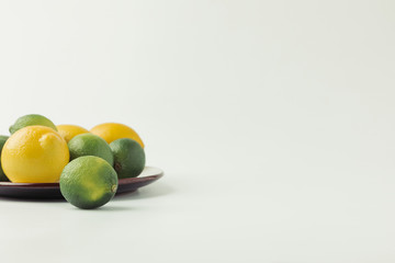 Green and Key limes on plate on white background