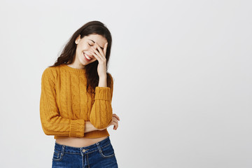 Portrait of attractive european girl in trendy cropped sweater smiling cheerfully while making face...