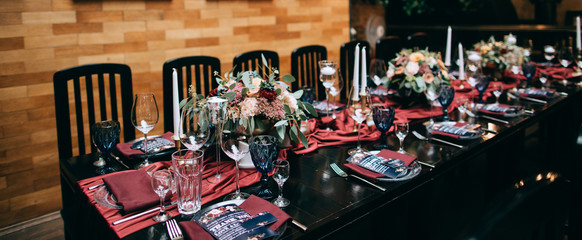 Wedding Banquet with red table setting decoration. Red tablecloth, white dishes, silver cutlery and red fresh flowers