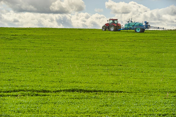 Fototapeta premium Tractor spraying pesticides on field with sprayer at spring