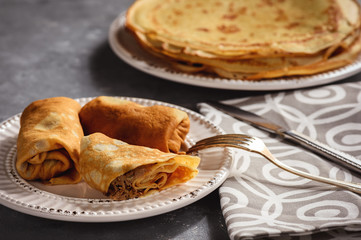 Pancakes stuffed with meat, on dark background.