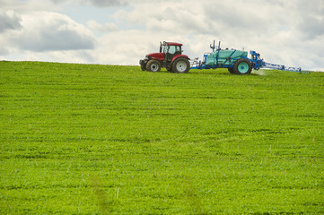 Fototapeta premium Tractor spraying pesticides on field with sprayer at spring