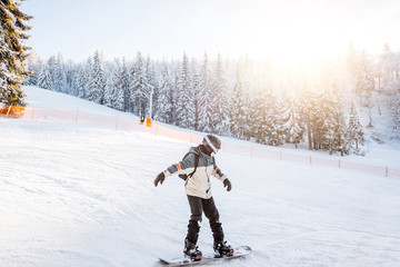 Landscape view on the snowy mountains with slopes and snowboarder riding during the sunny weather