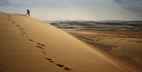 Photographer in sand dunes of Grand Sand Sea during desert safari in Egypt close to oasis Wahat Siwa