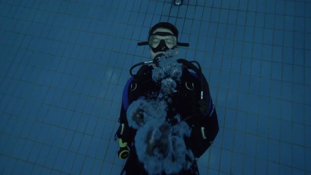 Man diver in scuba mask blowing underwater bubbles at training in diving lesson