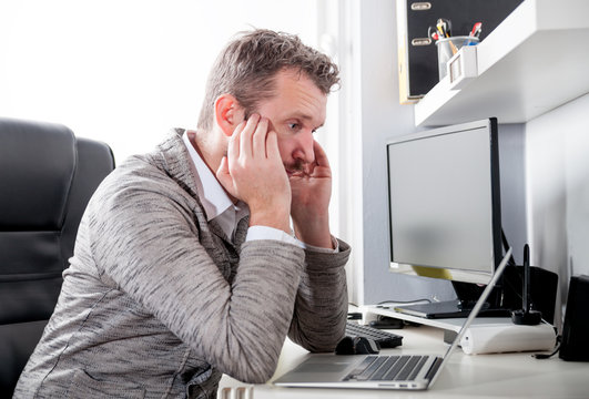 Tired man at workplace in office being unhappy