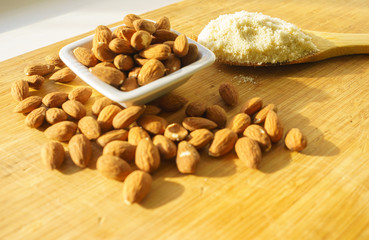 Almond flour in a wooden spoon on a background of nuts almonds.