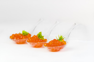 Plastic spoons with fish caviar on a white background. 