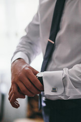 Man fixes watch on his wirst standing in the room