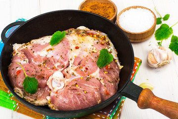 Frying pan with piece of raw meat with spices on white wooden table