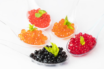 Plastic spoons with fish caviar on a white background. 