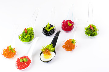 Plastic spoons with fish caviar on a white background. 