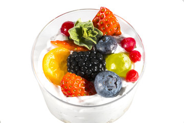 Creamy cream dessert in a plastic cup decorated with berries on a white background. 