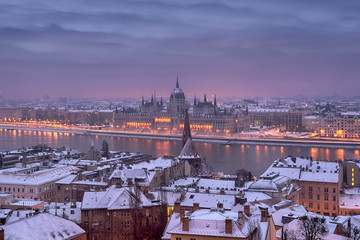 Break of the day in Budapest city in winter, roofs covered with snow, river, Parliament