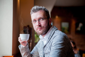 Confident man drinking cup of coffee in cafe
