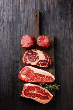 Variety of Raw Black Angus Prime meat steaks Blade on bone, Striploin, Rib eye, Tenderloin fillet mignon on wooden board