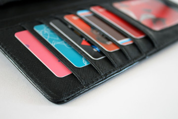 Opened black leather wallet with colourful credit, gift and discount cards closeup on white...