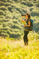 Young woman is hiking in mountain and enjoying nature. She is looking at map. 