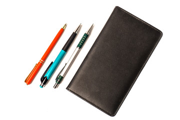 Black notebook with pen and pencils isolated on white background