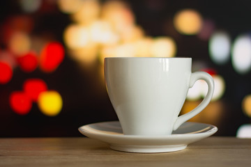 cup of coffee on wooden table with defocus bokeh of coffee shop background. Image with soft focus and blurred background.
