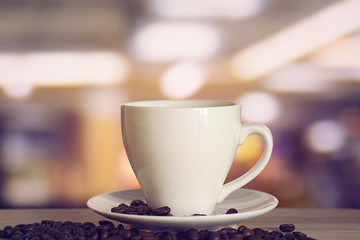 cup of coffee on wooden table with defocus bokeh of coffee shop background. Image with soft focus and blurred background.