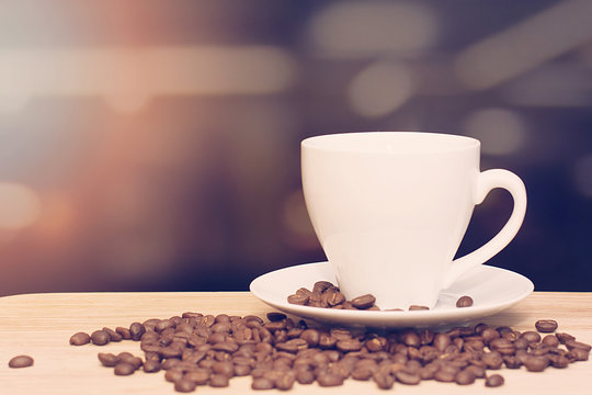 cup of coffee on wooden table with defocus bokeh of coffee shop background. Image with soft focus and blurred background.