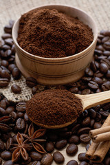 Coffee beans and ground coffee in a wooden spoon.