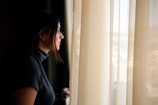 Young Woman Opening Curtains At Home