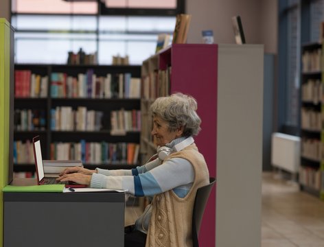 Senior woman using laptop in library