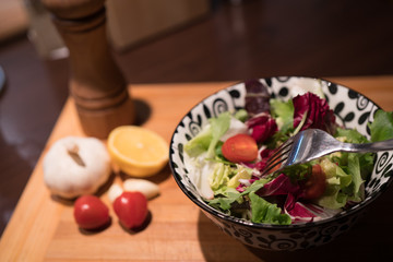 Fresh salad with garlic, tomato, lemon on wooden board