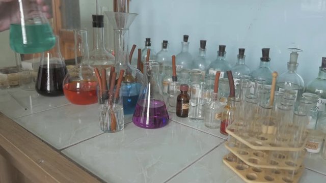 Chemical research. Scientist takes the flask with color liquids in lab in the University, College, School
