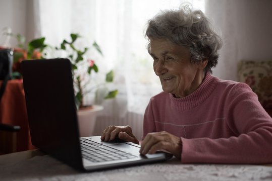 Smiling senior woman using a laptop while sitting at home
