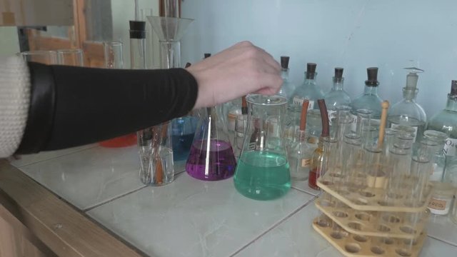 View of Chemist. Researcher stirring colorful liquid in flask by using glass rod
