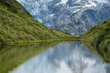 Fototapeta na wymiar The reflection of the rocky mountain with snow on the small lake on the high mountain in Mt Cook National Park (Muller hut track)