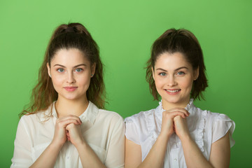 two beautiful positive girls with joyful emotions on a green background