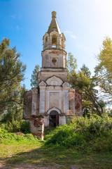 The ruins of old Christian Church on a background of bright trees and a blue sky