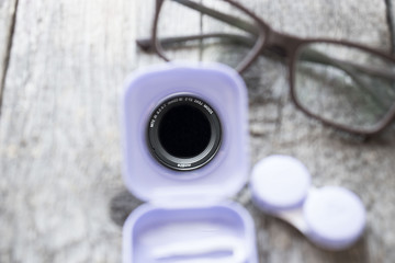 Contact lenses, tweezers on in pack on wooden background