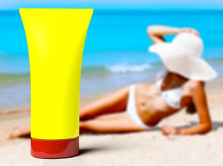 Woman in a swimsuit against the background of the blue sea and yellow bottle of sunblock cream or lotion