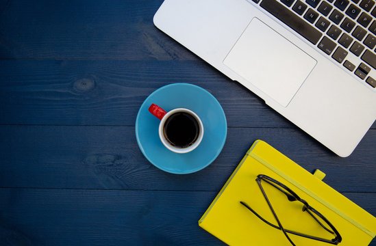 Laptop computer yellow notebook on blue wood desk background - Powered by Adobe