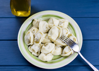 Boiled dumplings on a plate on a dark blue wooden background.