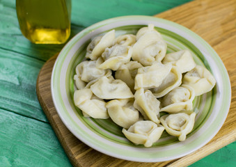 Boiled dumplings on a plate on a green wooden background.