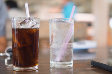 Soft drink and water in glass with ice