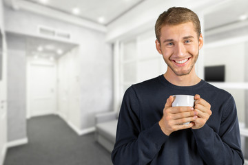 Young handsome man holding warm cup of tea/coffee