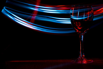 A glass of wine in night club. Red and blue blurred bands.