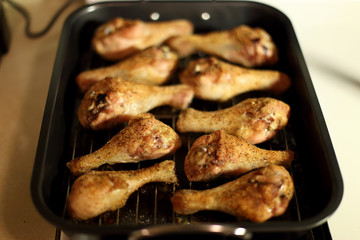 Baked chicken drumsticks cooling on top of a stove.