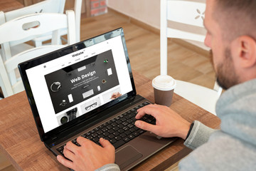 Fototapeta na wymiar Web design company responsive web site on laptop display. Guy watch site and drink coffee.